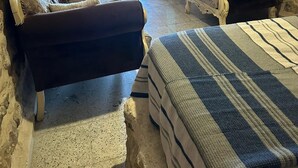 A stone-walled room with a sofa, armchairs, and a TV. - ACABEY KONAĞI (Mardin)