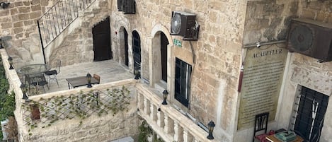 A stone building with multiple balconies, outdoor seating, and a sign indicating a restaurant.