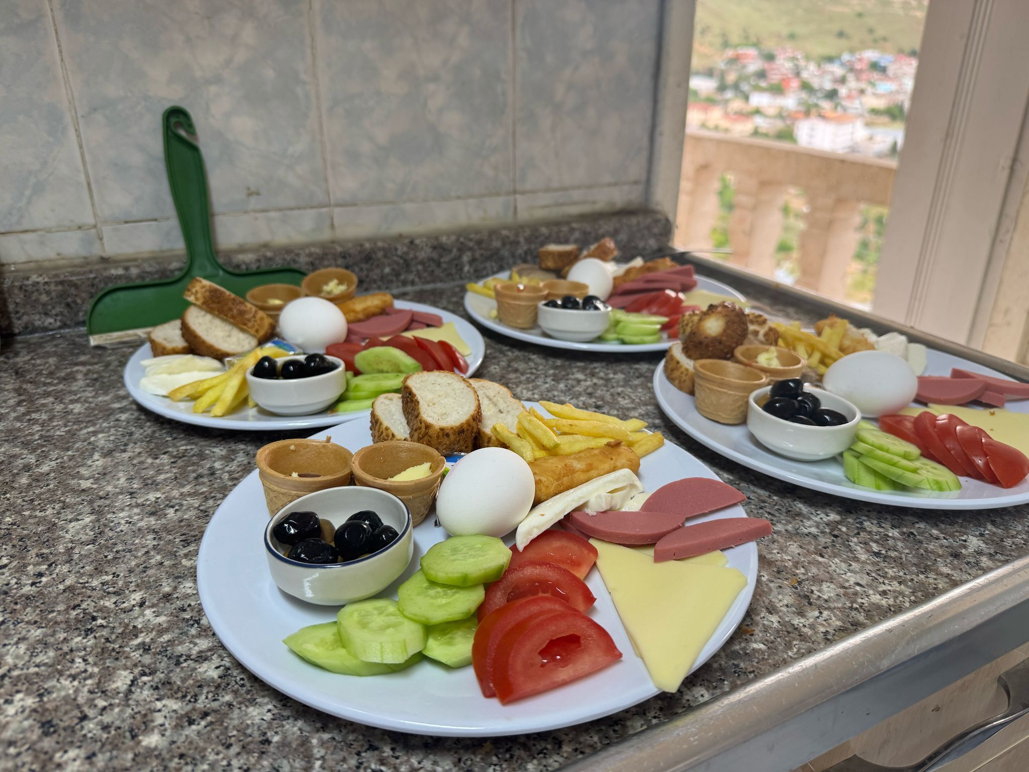 Een ontbijtbuffet met diverse gerechten, zoals brood, eieren, kaas, tomaten, komkommers en olijven.