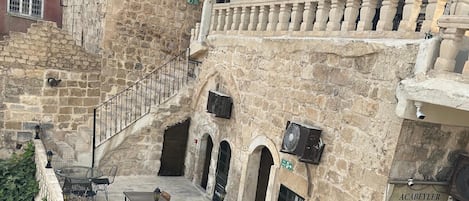 A multi-story building with stone walls, balconies, and outdoor seating areas.