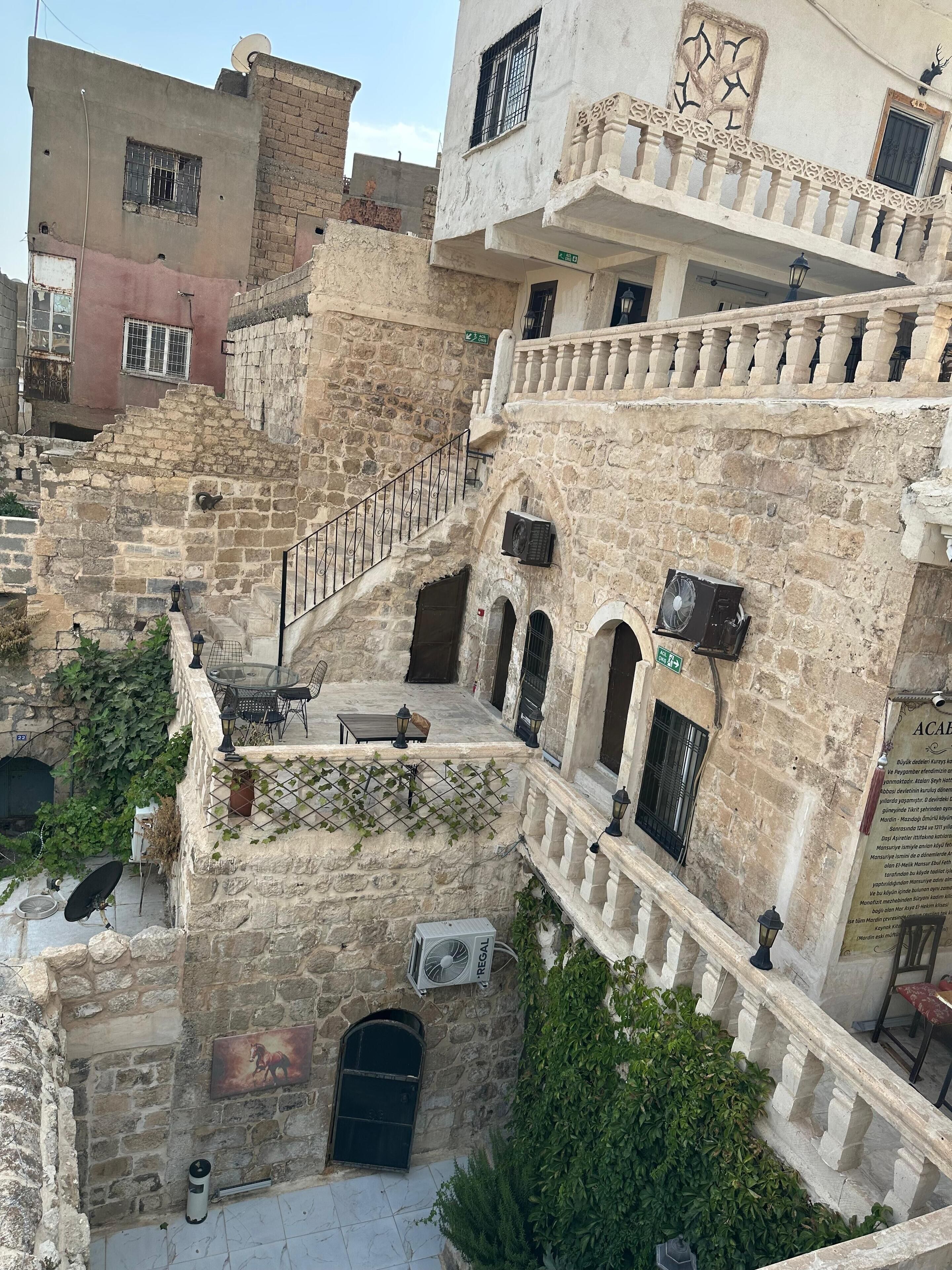 A multi-story building with stone walls, a staircase, and outdoor seating.