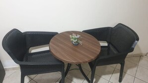 A small round table with a dark wood finish and a potted plant. Two black mesh chairs with a curved backrest are positioned around the table. - Superb studio at the ocean (Rabat)