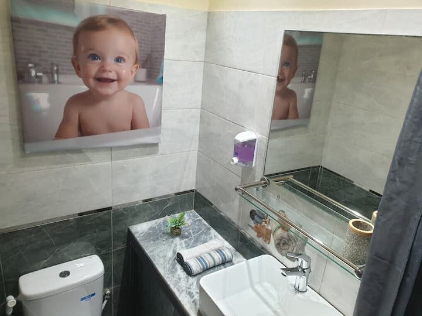 A modern bathroom with a marble countertop, a toilet, a sink, and a glass shower enclosure.