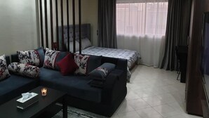 A modern hotel room with a sofa, a bed, a TV, and a partition wall. - Superb studio at the ocean (Rabat)