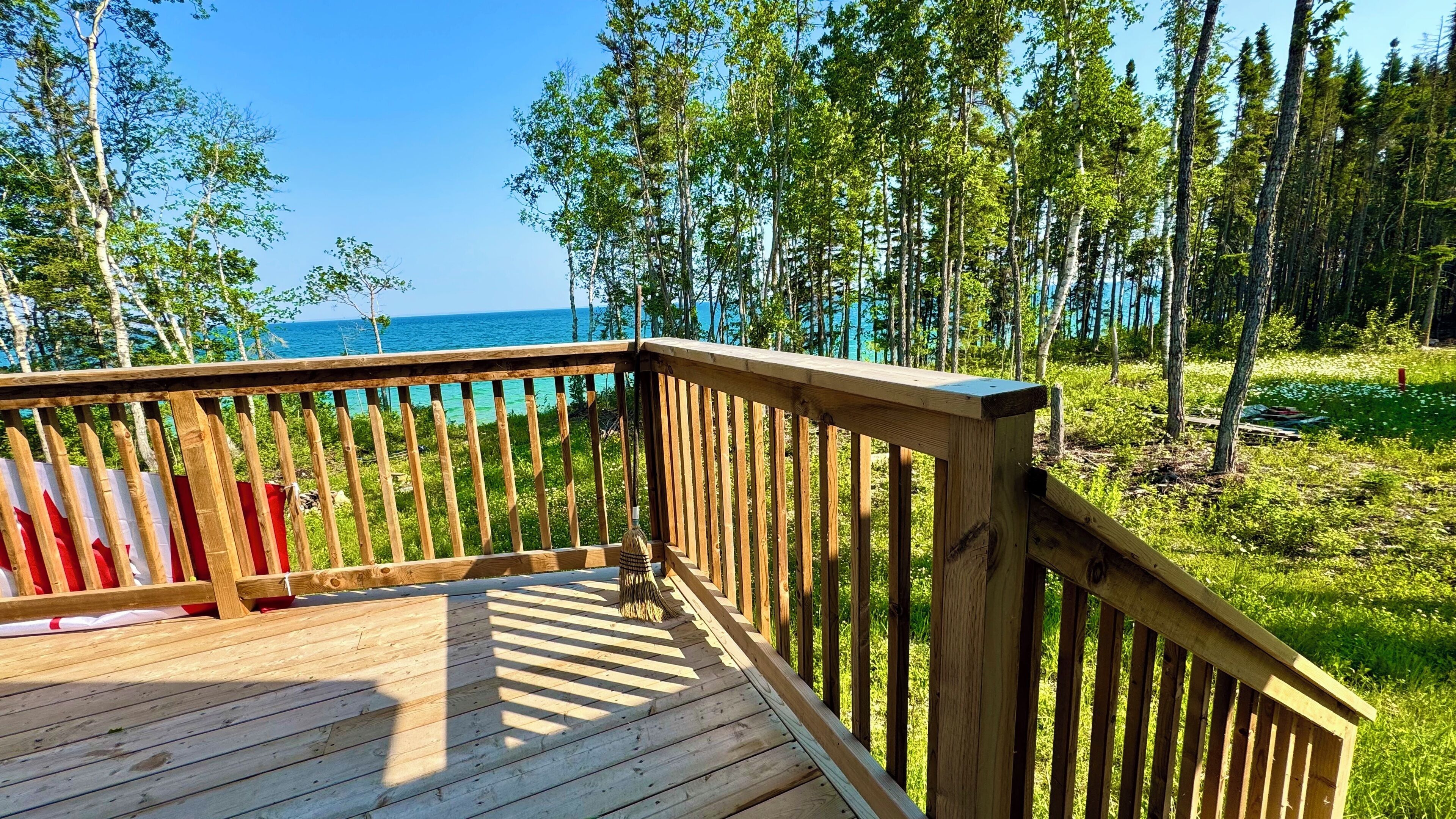 A wooden deck with a view of the ocean and a forest.