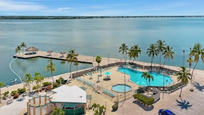 A resort with a large pool, palm trees, and a view of the ocean.