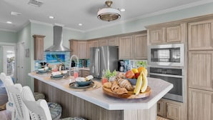 A modern kitchen with a large island, stainless steel appliances, and wooden cabinetry.