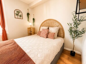 A bedroom with a bed, a bedside table, a lamp, a wall-mounted plant, and a potted plant.