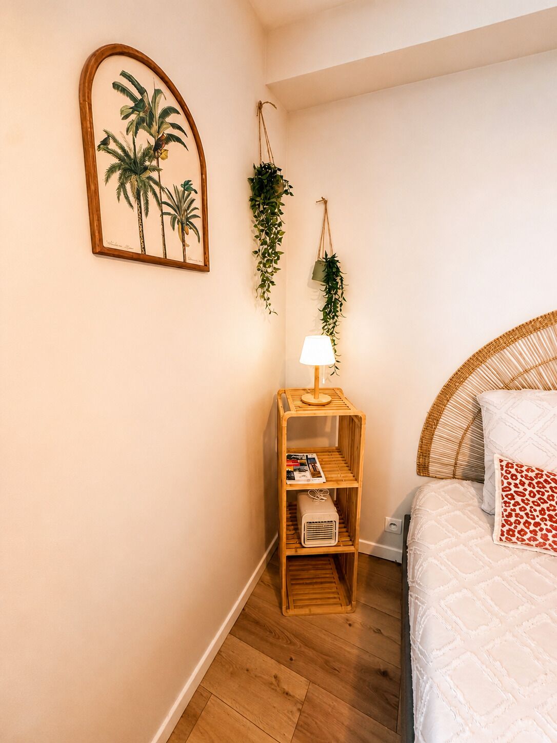 Ein Schlafzimmer mit einem Bett, einem Nachttisch mit Lampe, einer wandmontierten Pflanze und einem gerahmten Bild.