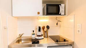 Una cocina compacta equipada con microondas, pileta y lavavajillas pequeño.
