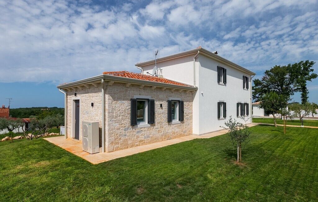 Una casa de dos plantas con fachada de piedra y tejado de tejas rojas.