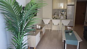 A modern kitchen with white cabinets, a countertop, and a dining area with a table and chairs. - Troya Beach Apartments (Playa de la Américas)