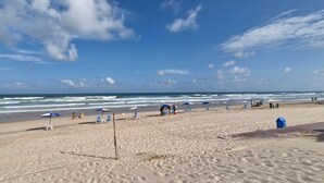 A beach with umbrellas, chairs, and a sandy shore.