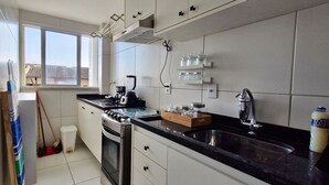 A modern kitchen with stainless steel appliances, a black countertop, and a window providing natural light.