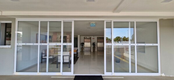 Entrada de un hotel con puerta de vidrio, mostrador de recepción y un letrero con el nombre del hotel.
