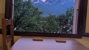 Una mesa de madera con vistas a las montañas a través de un amplio ventanal.
