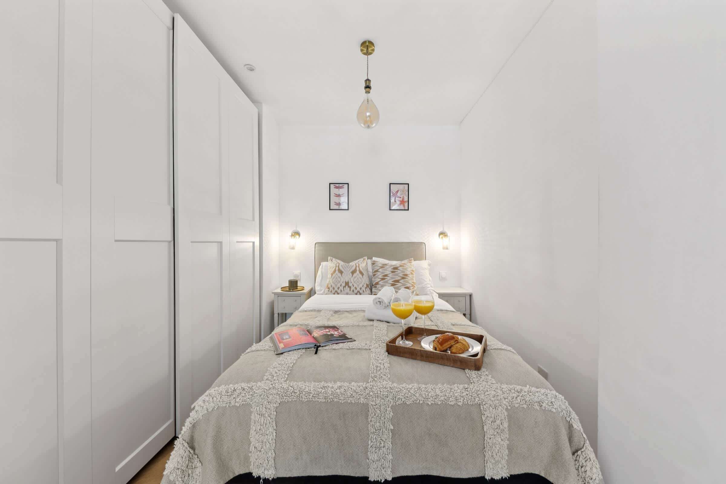 Une chambre à coucher bien rangée, avec un lit, des tables de chevet et un plateau contenant des éléments pour le petit-déjeuner.