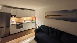 Une cuisine compacte dotée d’appareils électroménagers modernes, un coin repas et un canapé.