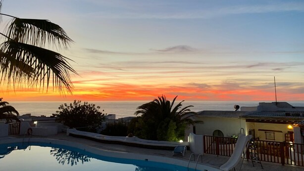 Une piscine avec vue sur le coucher de soleil, un toboggan et un poste de surveillance pour les sauveteurs.