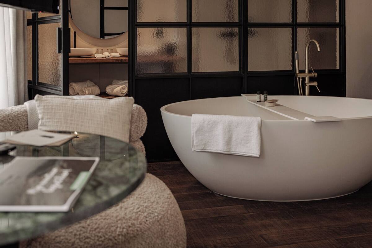 Une salle de bain moderne avec une baignoire sur pieds, une table en verre avec un livre et un porte-serviettes.