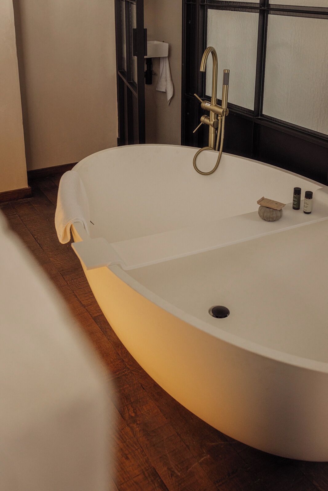 A modern bathroom with a freestanding bathtub, a towel rack, and a window with frosted glass.