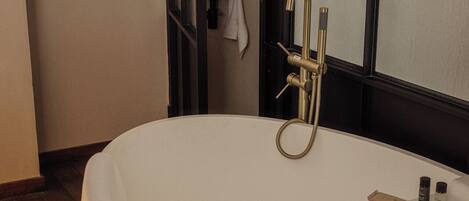 A modern bathroom with a freestanding bathtub, a towel rack, and a window with frosted glass.
