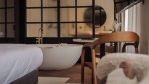 Un dormitorio moderno con una bañera grande, una silla de madera y una cama.