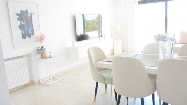 A bright, modern dining area with a white table, chairs, and a large window providing natural light. - Luxury 3bedrooms apartment in Gammarth Touristique with Pool 3 Mnts beach access (Gammarth)