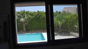 A window with a view of a swimming pool surrounded by lush greenery. - Luxury 3bedrooms apartment in Gammarth Touristique with Pool 3 Mnts beach access (Gammarth)
