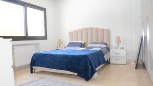 A bedroom with a bed, bedside tables, a window, and a radiator. - Luxury 3bedrooms apartment in Gammarth Touristique with Pool 3 Mnts beach access (Gammarth)