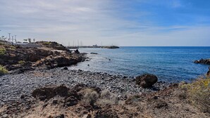 Una costa rocosa con cielo despejado y mar tranquilo.