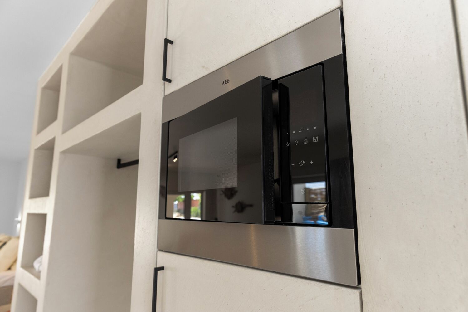 Un four à micro-ondes encastré doté d’un panneau de commande numérique, intégré à un meuble de cuisine blanc.