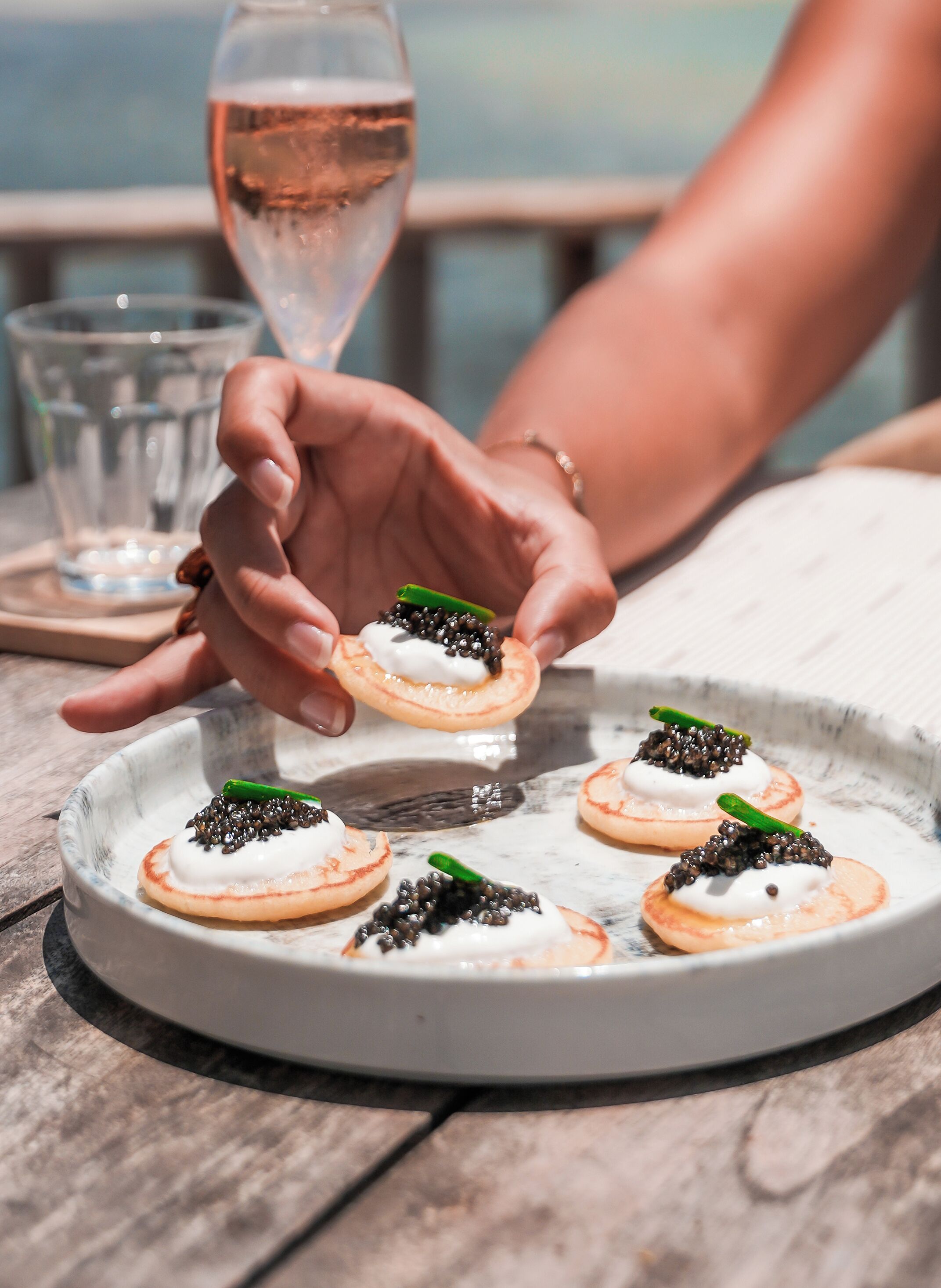 A plate with food items and a glass of water on a wooden table.