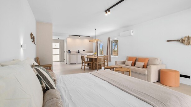 A spacious bedroom with a large bed, a sofa, and a dining area. - Sorobon Bay Hotel (Kralendijk)