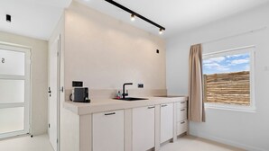 A modern kitchen with a built-in coffee maker, a sink, and a window with a view of the sky. - Sorobon Bay Hotel (Kralendijk)