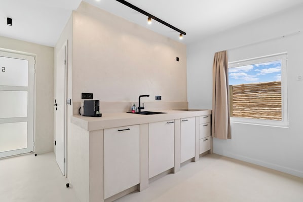 A modern kitchen with a built-in coffee maker, a sink, and a window with a view of the sky. - Sorobon Bay Hotel (Kralendijk)