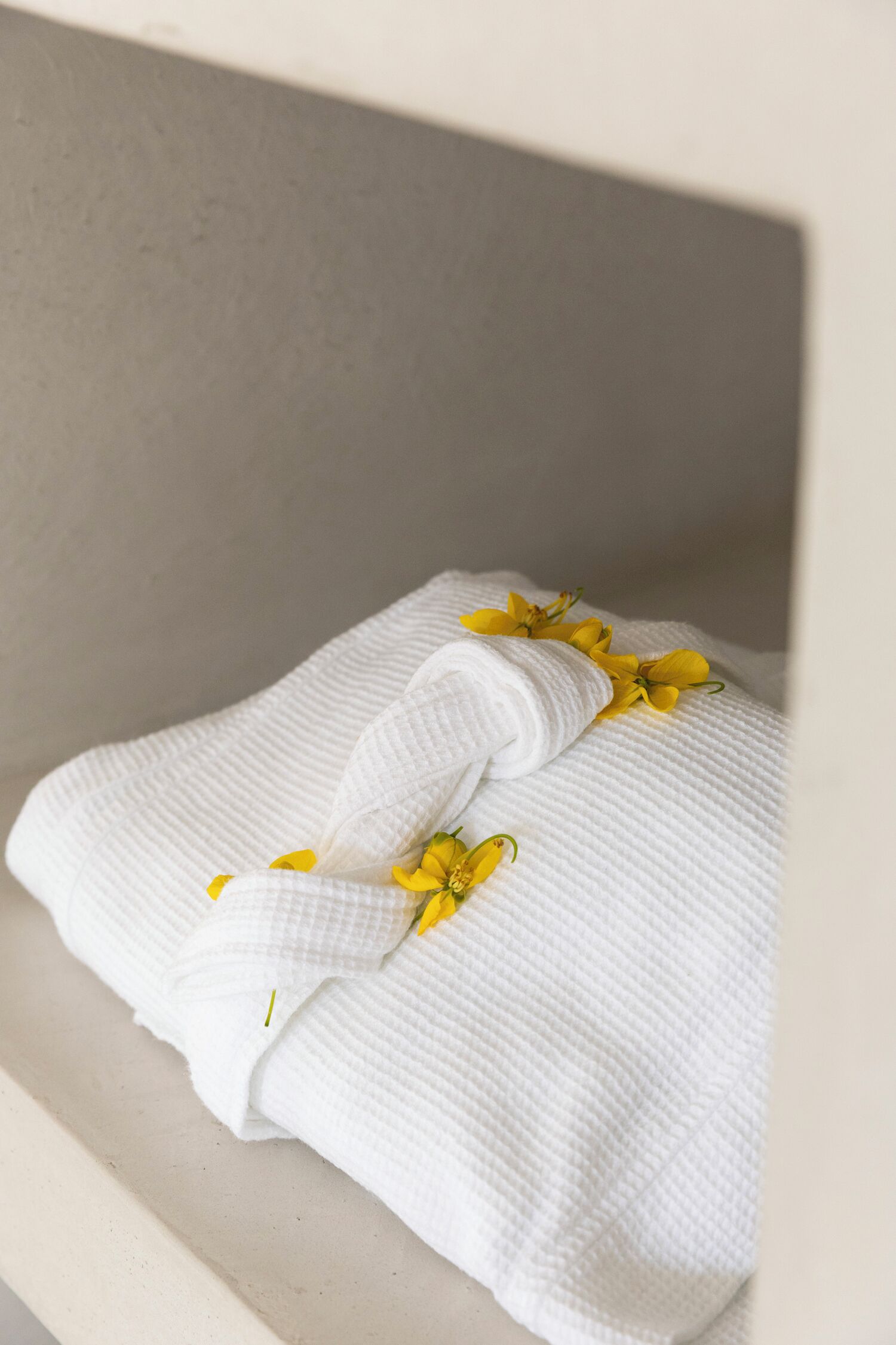 A neatly folded white towel with yellow flowers on a white shelf.