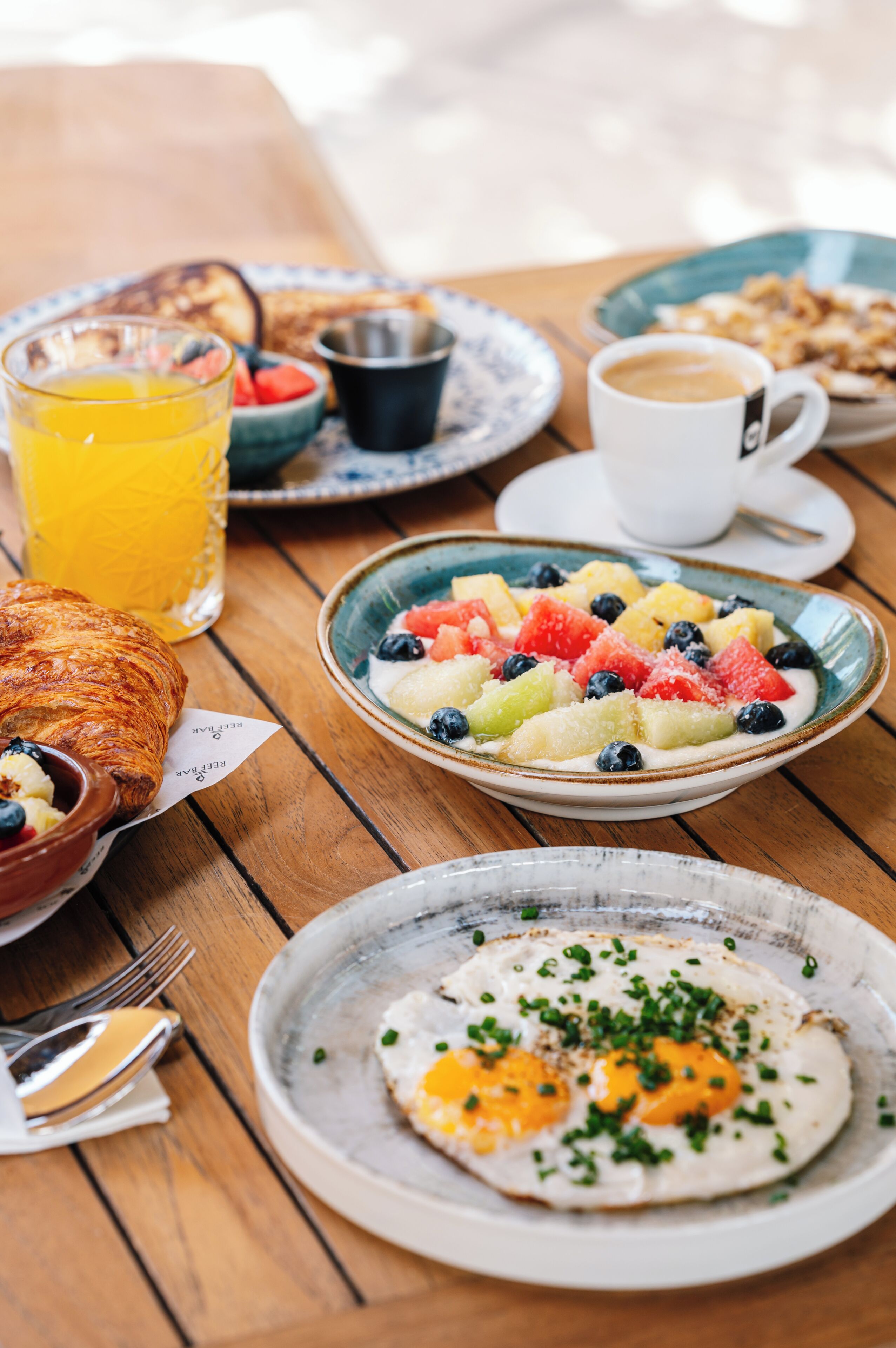 Un desayuno con cruasanes, fruta, café y un cruasán con mantequilla.