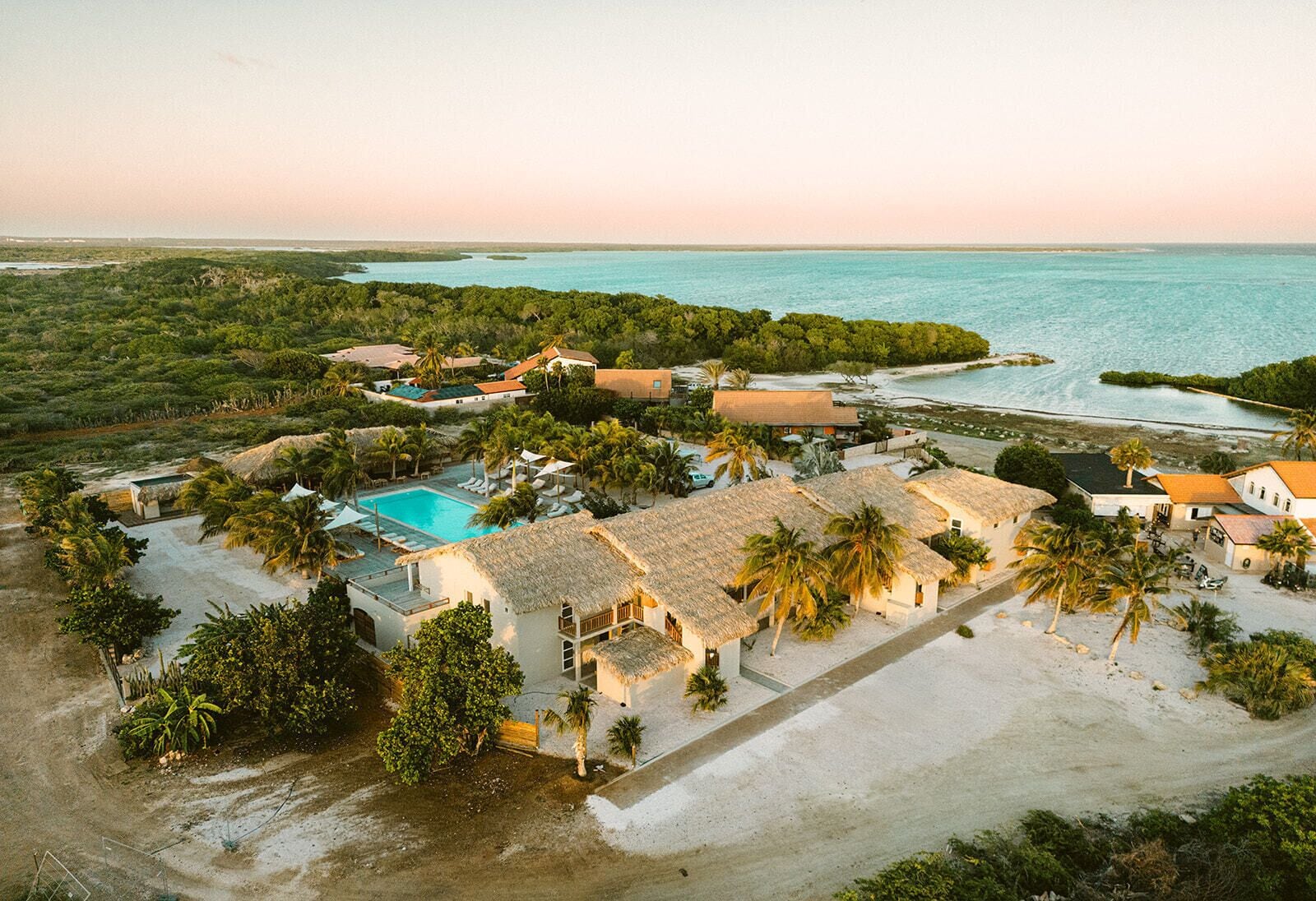 Un resort con piscina, villas frente a la playa y vista al océano.