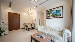 A modern living room with a white sofa, a wooden coffee table, and a dining area with a table and chairs.