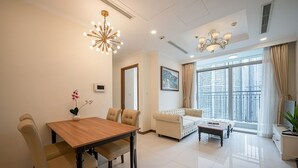 A modern living room with a dining area, large windows, and a chandelier.