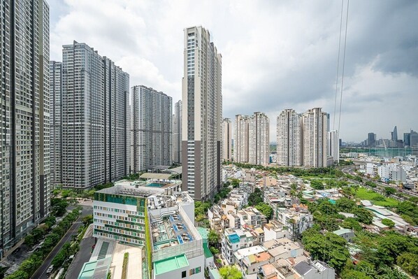 A high-rise residential area with modern apartment buildings, a central open space, and a view of the city skyline.