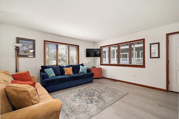 A living room with a blue sofa, beige sofa, and a patterned rug.