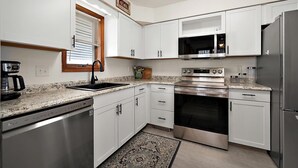 A kitchen with white cabinets, a stainless steel refrigerator, a built-in oven, and a microwave.
