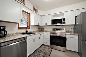 A kitchen with white cabinets, a stainless steel refrigerator, a built-in oven, and a microwave.