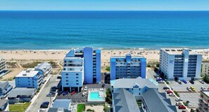 Ein Küstenhotel mit mehreren Gebäuden, einem Parkplatz und Blick auf den Strand.