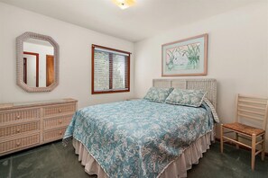 A bedroom with a bed, a dresser, a chair, a window with blinds, a mirror, and a framed picture on the wall.