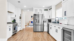 A modern kitchen with white cabinetry, stainless steel appliances, and a wooden floor. - Newly Renovated, Spacious & Modern | THE (Rockwall)