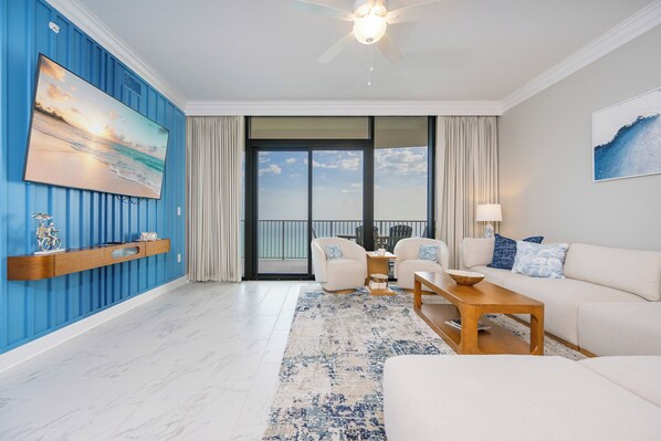 A modern living room with a blue accent wall, a large window, and a balcony.