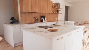 Una cocina moderna con armarios blancos, encimera de mármol y una isla integrada.